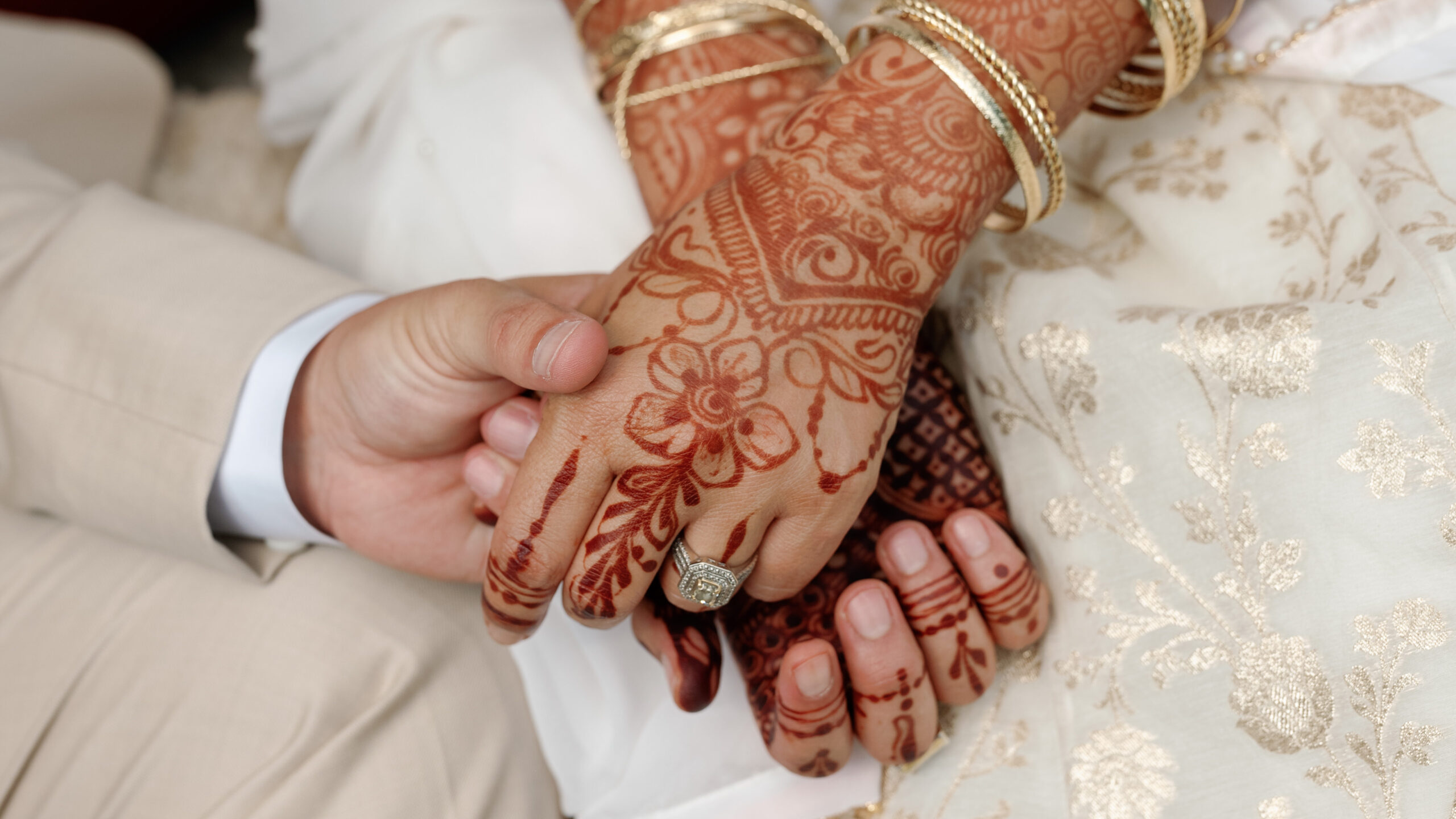 South asian newlyweds under a mandap holding hands